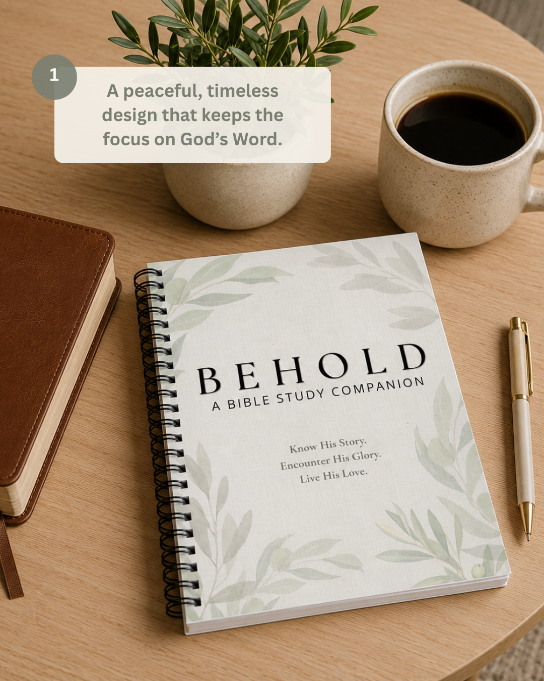 A spiral-bound Bible study companion notebook titled 'BEHOLD' lies on a light wood table, surrounded by a coffee cup, a brown leather journal, a pen, and a small potted plant. A text callout in the upper left describes the notebook's design.